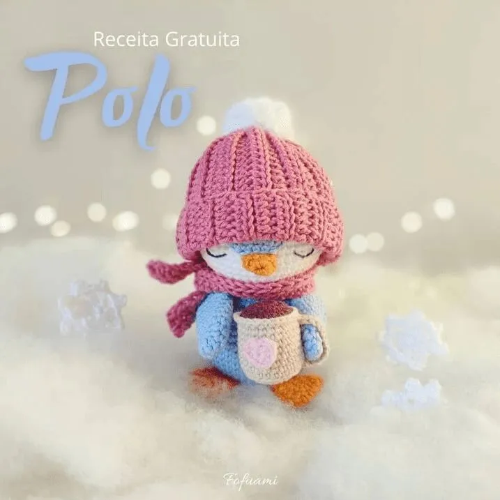 Un Pingüino De Crochet Con Un Gorro Y Una Bufanda De Punto Rosa Sostiene Una Taza Con Un Diseño De Corazón De Pie Sobre Una Superficie Blanca Y Esponjosa El Texto Lee receita Gratuita Polo Las Decoraciones De Copos De Nieve Y La Iluminación Tenue Crean Un Ambiente Acogedor De Invierno Perfecto Para Quienes Buscan Una Solución Gratuita De Amigurumi