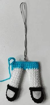 Un Adorno De Crochet Hecho a Mano Inspirado En Las Chicas Superpoderosas Que Presenta Diminutos Pantalones Blancos Con Zapatos Negros Y Una Cinturilla Azul Los Pantalones Están Sujetos a Un Lazo De Metal Retorcido Para Colgarlos La Artesanía Se Detalla Con Puntadas Visibles Y Un Hilo Azul Suelto