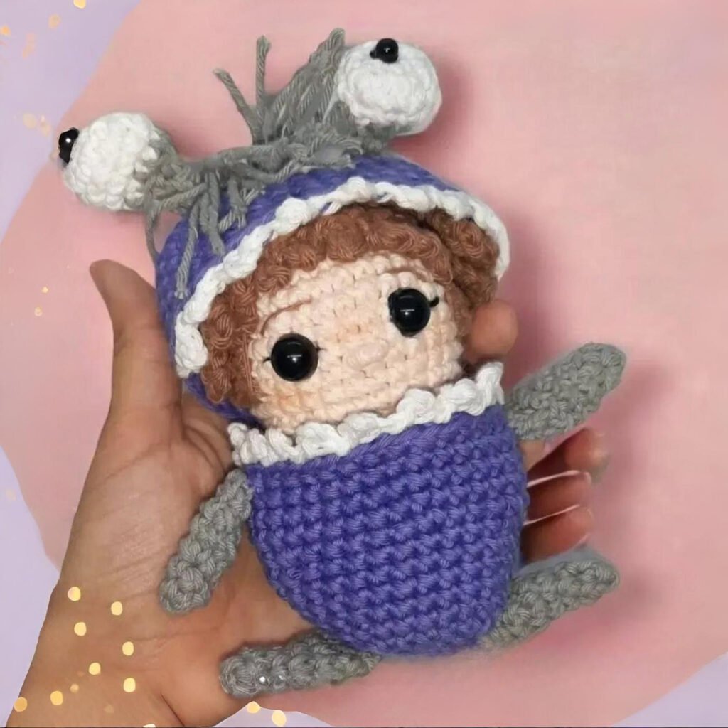 Muñeca amigurumi de Boo de Monsters Inc con su disfraz de monstruo violeta tejido a crochet, vista frontal y detalles del cabello