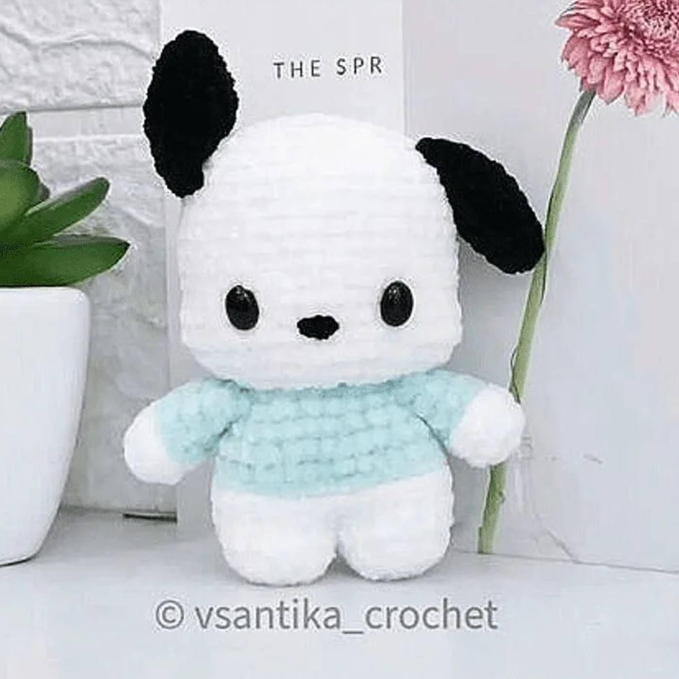 Amigurumi de Pochacco tejido a crochet, perrito blanco y negro de Sanrio con ropa azul, vista frontal terminado