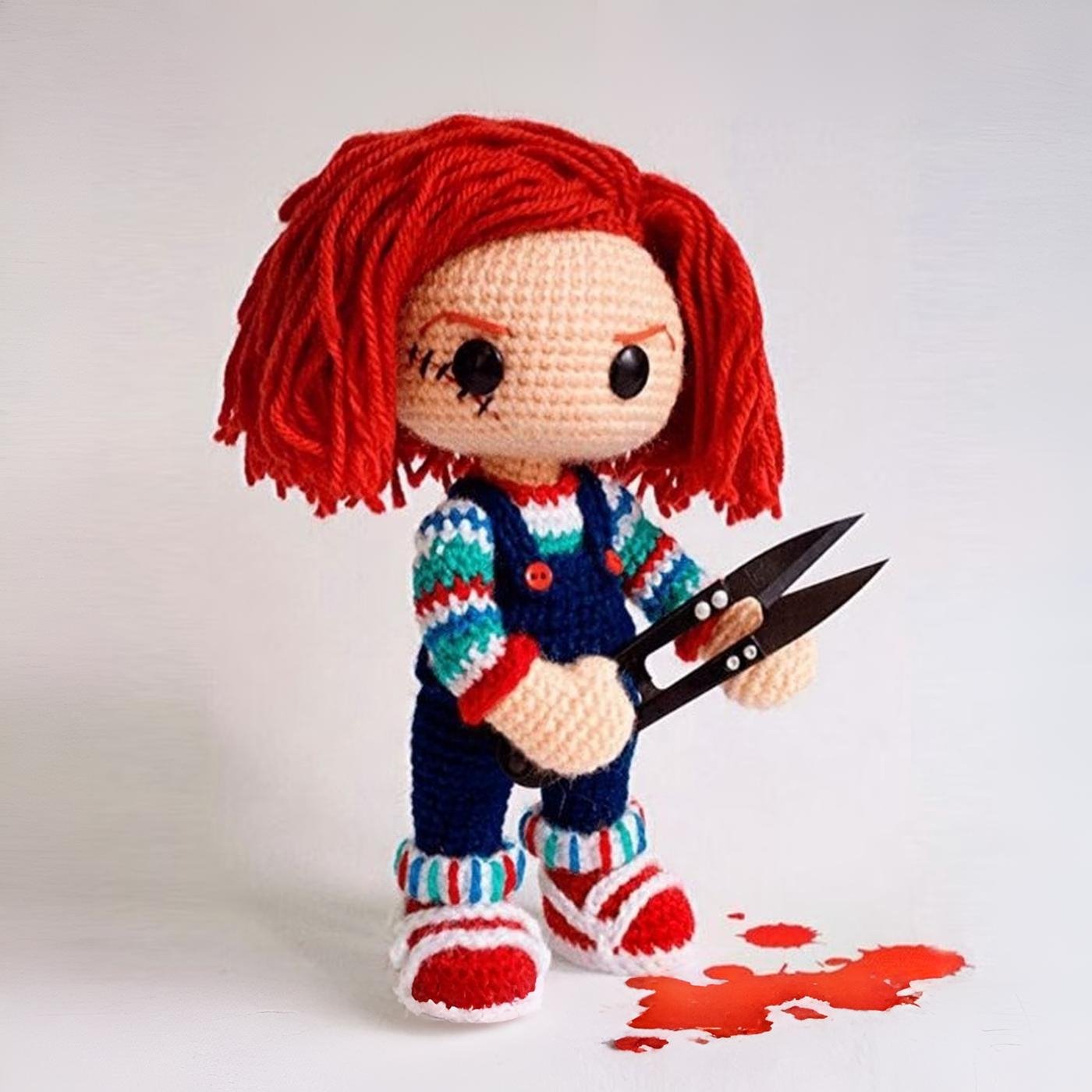 Muñeco amigurumi de Chucky tejido a ganchillo terminado, con su overol azul y pelo rojo característico.