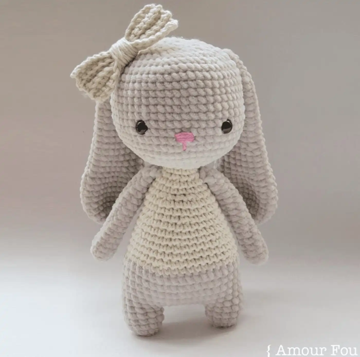 Bruna, una adorable conejita amigurumi terminada, sentada con su lazo en la cabeza.