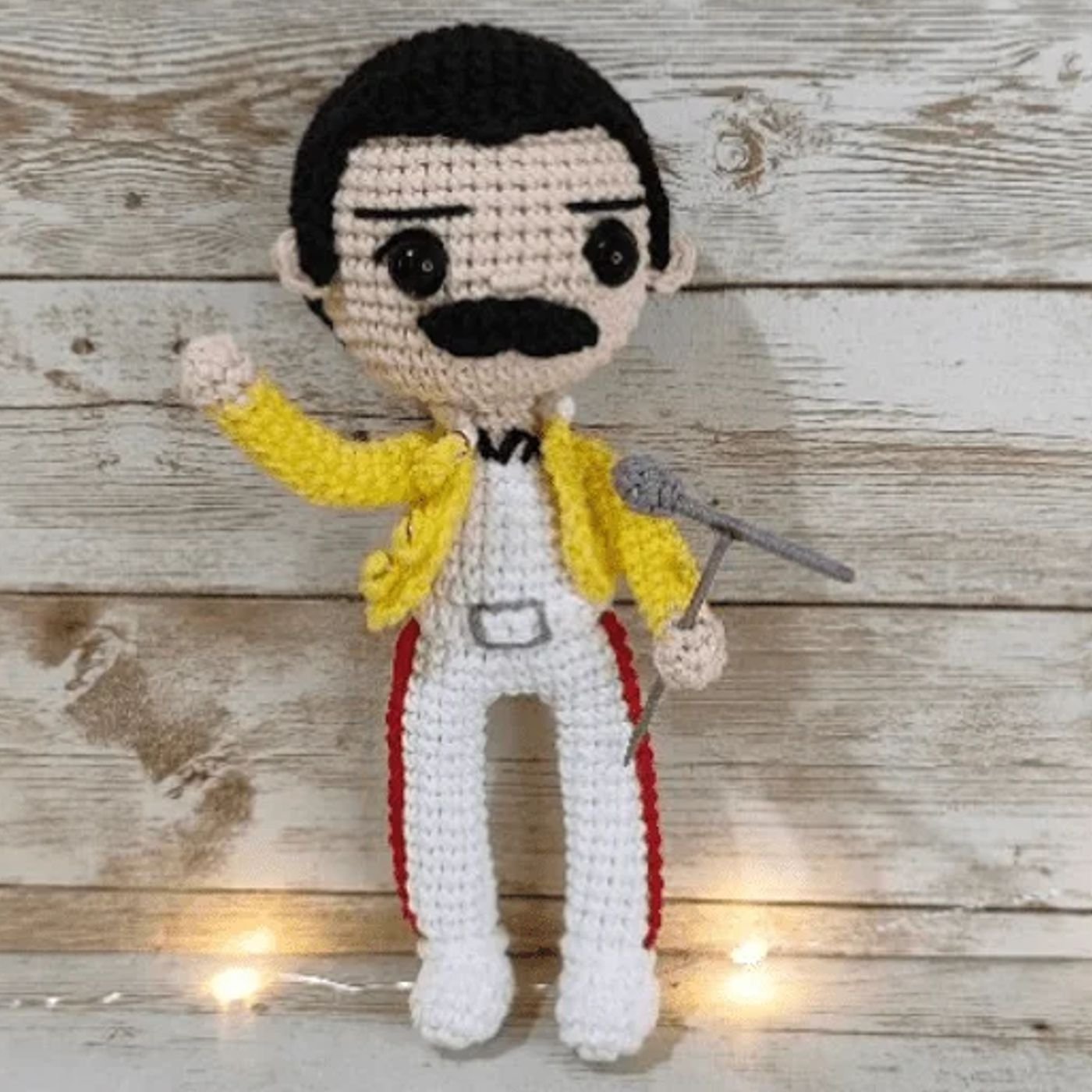 Muñeco amigurumi de Freddie Mercury tejido a ganchillo, posando con su chaqueta amarilla y micrófono.