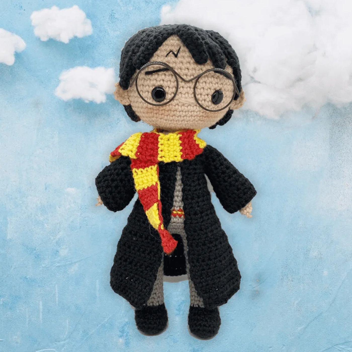 Muñeco amigurumi de Harry Potter tejido a ganchillo, con su cicatriz, gafas y bufanda de Gryffindor.