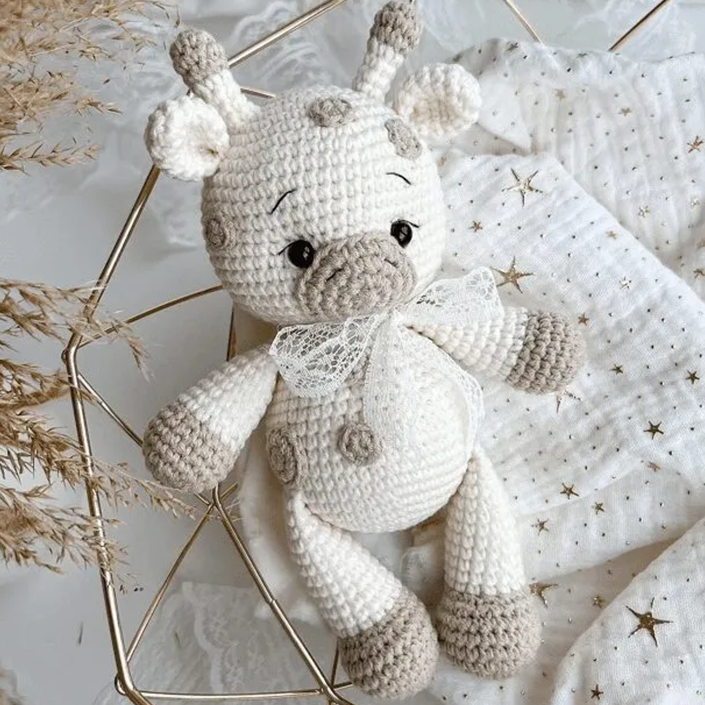 Jirafa amigurumi terminada, tejida a ganchillo con hilo de color beige y marrón, sentada sobre un fondo claro.
