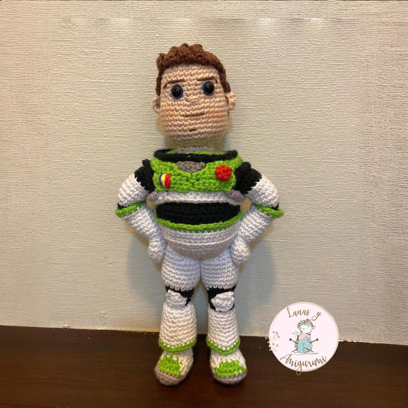 Buzz Lightyear amigurumi terminado, muñeco tejido de crochet con traje espacial blanco, verde y morado, de pie sobre una superficie de madera.