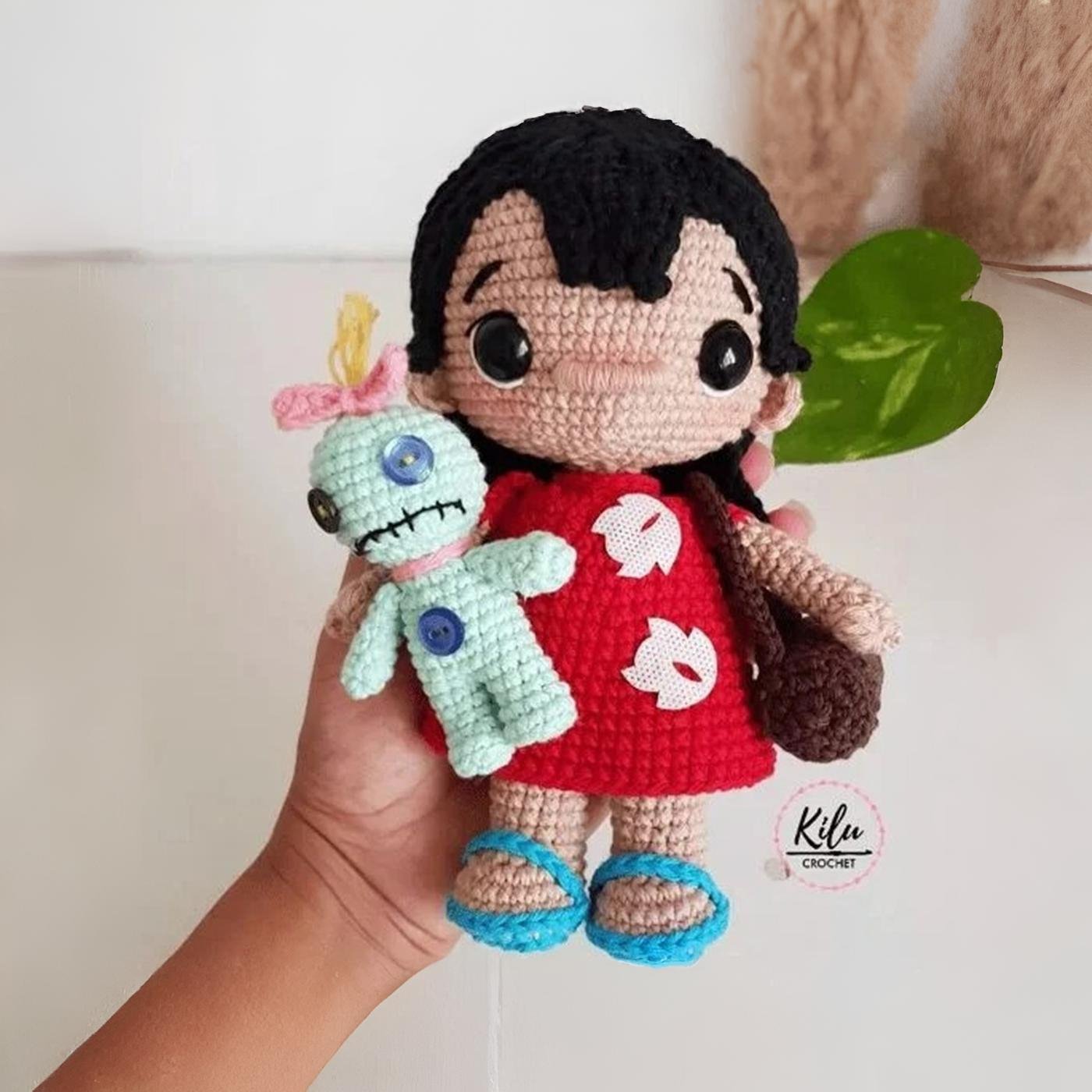Muñeca amigurumi de Lilo del personaje de Lilo y Stitch, tejida a ganchillo, con su vestido rojo y su muñeca Trapos.