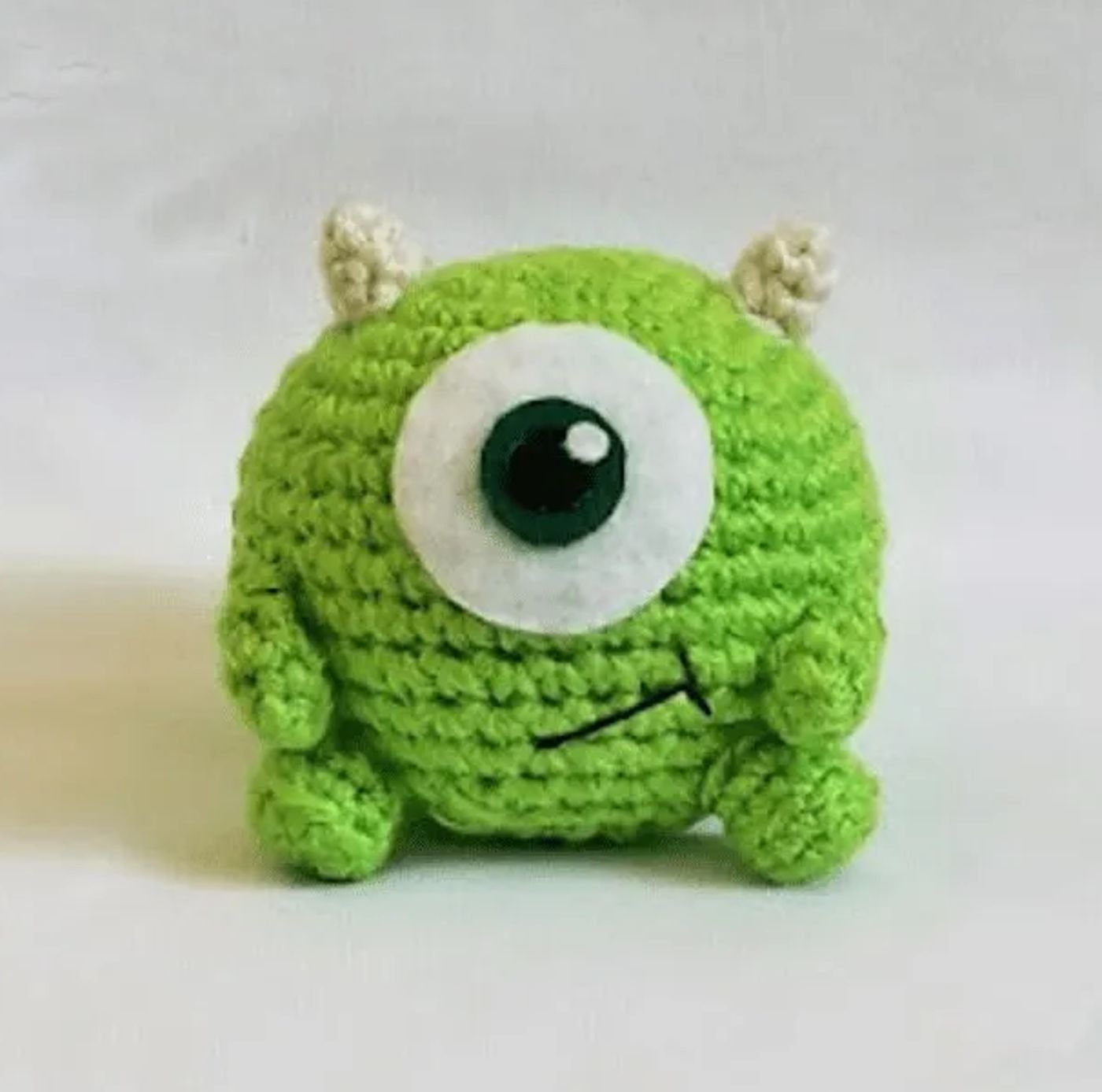 Muñeco amigurumi de Mike Wazowski tejido a ganchillo sobre un fondo blanco