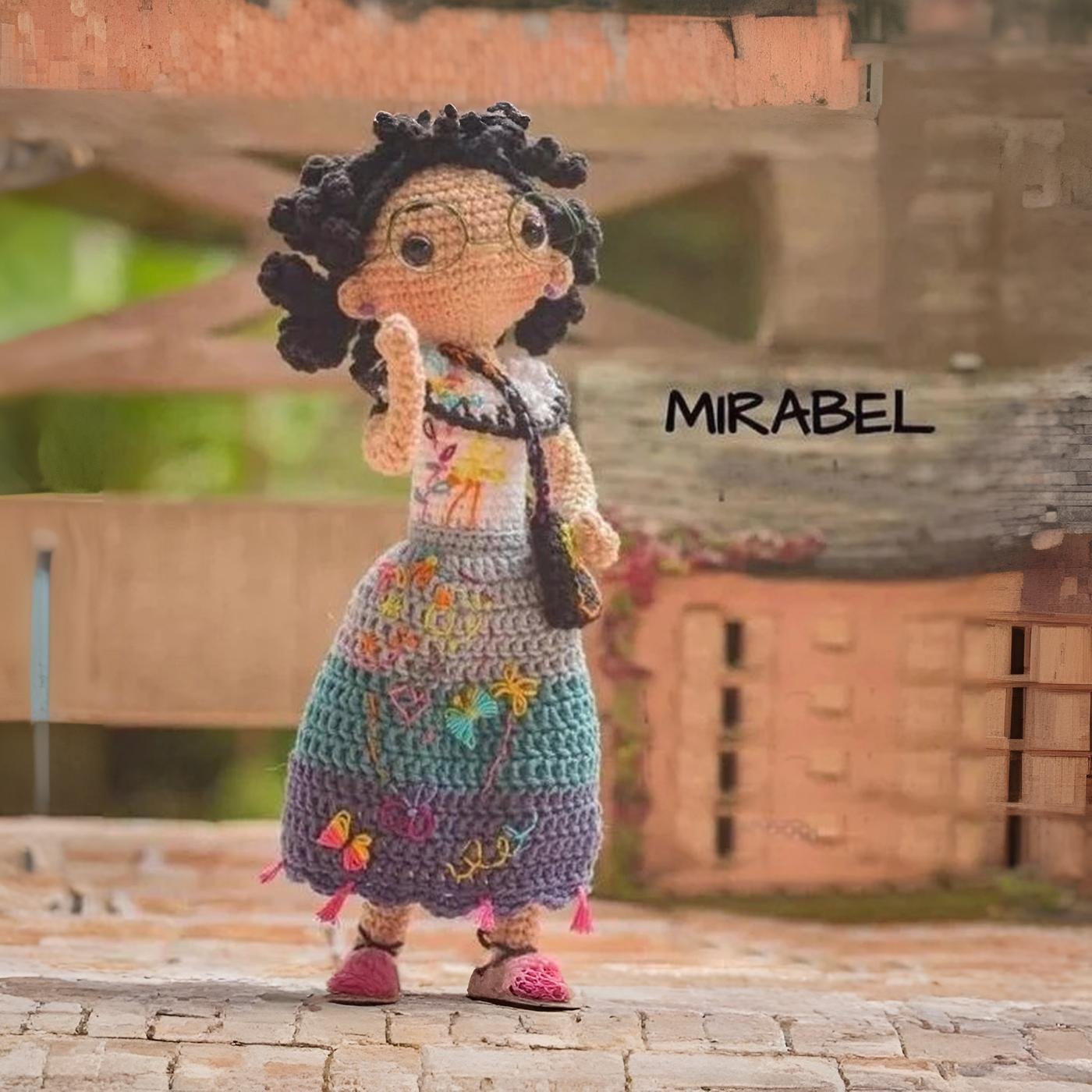 Muñeco amigurumi de Mirabel Madrigal de la película Encanto, tejido a ganchillo con su vestido de colores y gafas verdes.