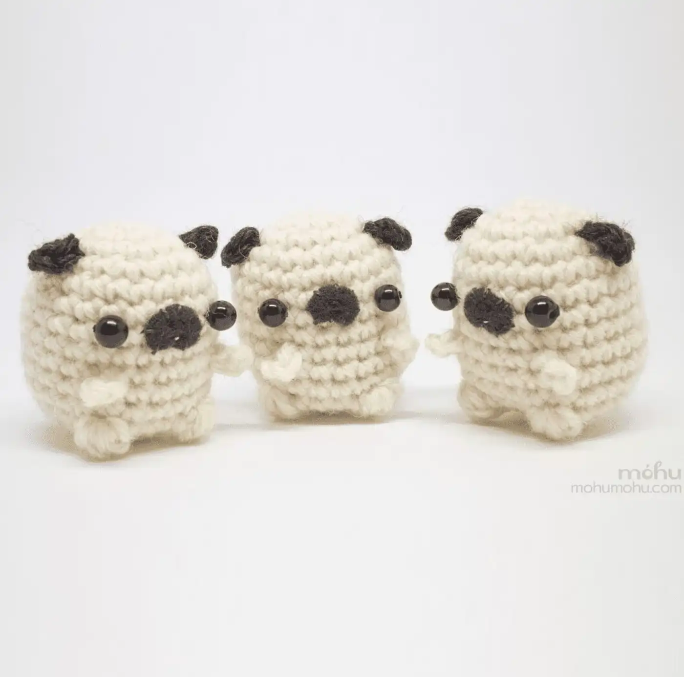 Adorable perrito pug amigurumi tejido a crochet sentado junto a un ovillo de lana.