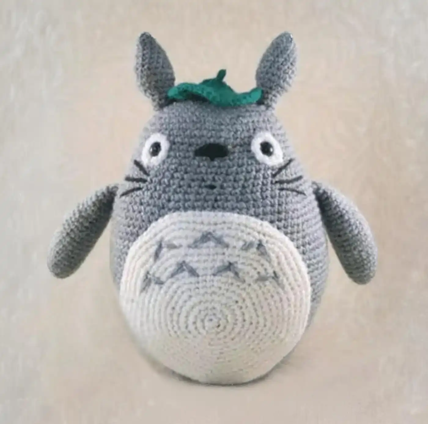 Muñeco tejido de Totoro amigurumi hecho a ganchillo, mostrando su barriga blanca y su gran sonrisa.