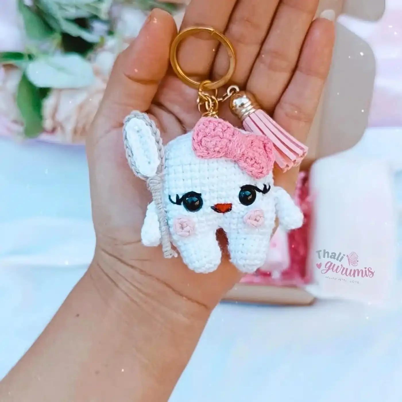 Diente amigurumi tejido a crochet con cepillo de dientes y lazo rosa, ideal para llavero