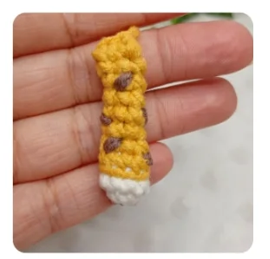 Una pequeña pata tejida a crochet para un amigurumi Zayu, con detalles amarillos, manchas marrones y punta blanca.