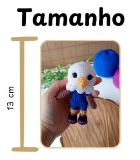 Muñeco amigurumi de águila blanca y azul, mascota Clutch, sostenido en una mano con una guía de medida de 13 cm.