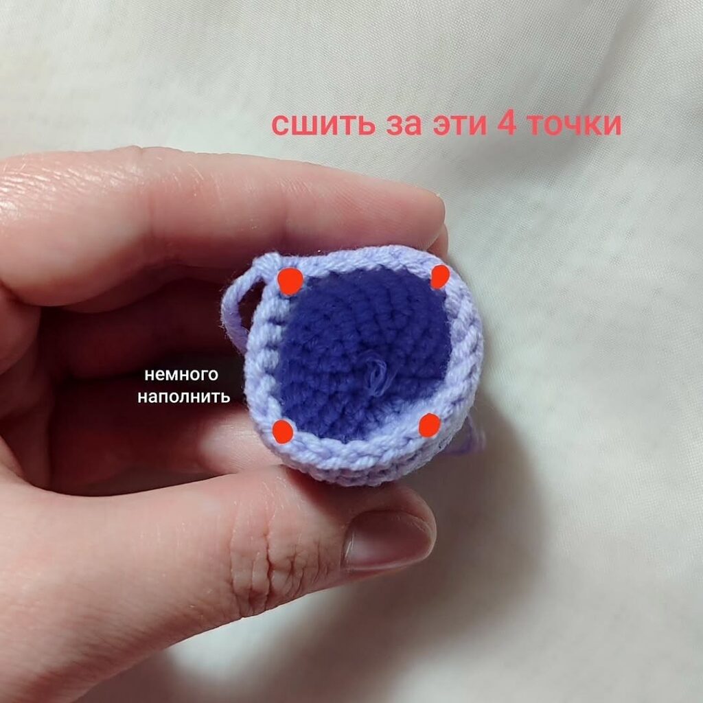 Primer Plano De Una Pieza De Amigurumi Morada Tejida a Crochet Cuatro Puntos Marcados Para Coser Instrucciones Coser En Estos Cuatro Puntos Y Rellenar Ligeramente
