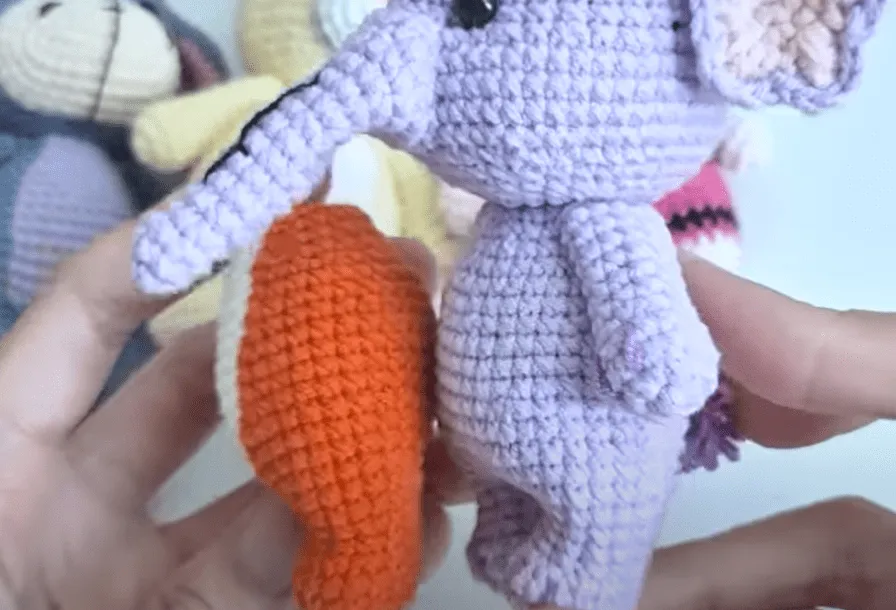 Primer plano de dos animales amigurumi tejidos a crochet: un elefante lavanda y un zorro naranja.