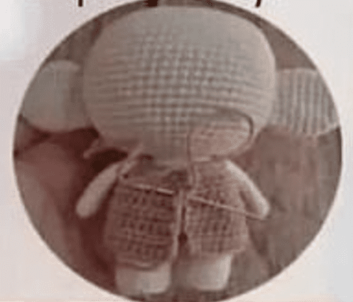 Un Muñeco De Crochet Dobby De Harry Potter Con Cabeza Redonda Grandes Orejas Redondas Y Cuerpo Pequeño El Muñeco De Peluche Aparece Sin Terminar Con Puntadas E Hilos Visibles El Fondo Es De Un Color Neutro Y La Imagen Tiene Un Marco Circular