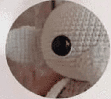 Primer Plano De Un Tejido De Peluche De Crochet Que Recuerda a Dobby De Harry Potter Con Un Gran Ojo De Botón Negro La Textura Y El Patrón Del Hilo Son Visibles Con El Fondo Borroso La Forma General Y Los Detalles Del Objeto No Son Completamente Visibles Dentro Del Marco Circular