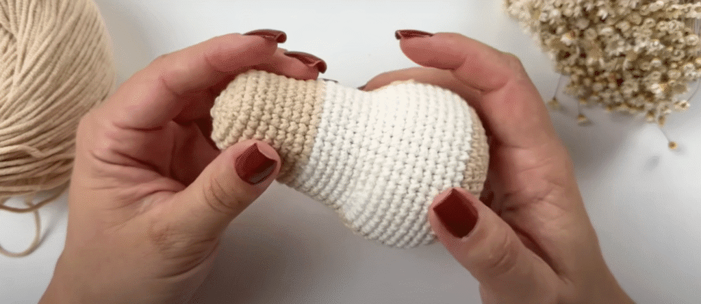 Manos Sosteniendo Un Conejito Amigurumi Tejido a Crochet Parcialmente Beige Y Blanco