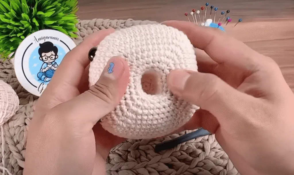 Primer plano de unas manos sosteniendo un amigurumi tejido a crochet, mostrando un agujero en el centro.