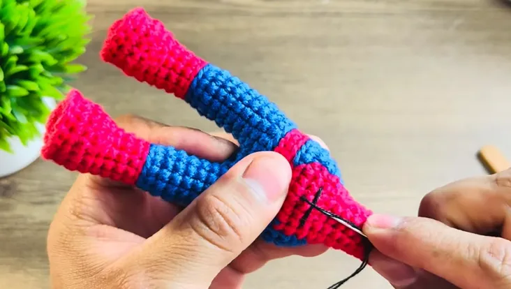 Primer plano de manos tejiendo un juguete amigurumi de Spiderman.