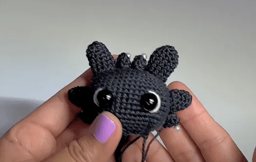 Primer plano de un ajolote negro tejido a crochet con detalles de perlas.