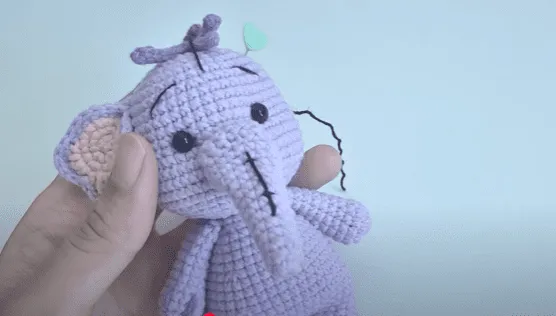 Primer plano de un juguete amigurumi de elefante morado tejido a crochet.