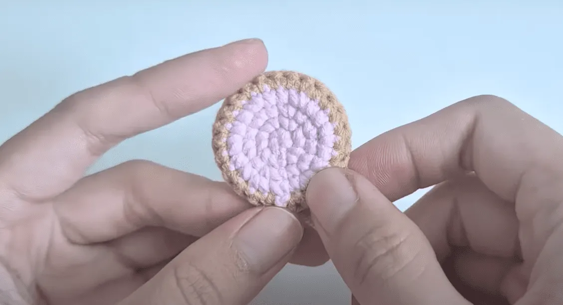 Primer plano de unas manos sosteniendo una pequeña galleta tejida a crochet.