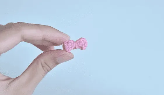 Primer plano de un pequeño lazo de crochet de color rosa.