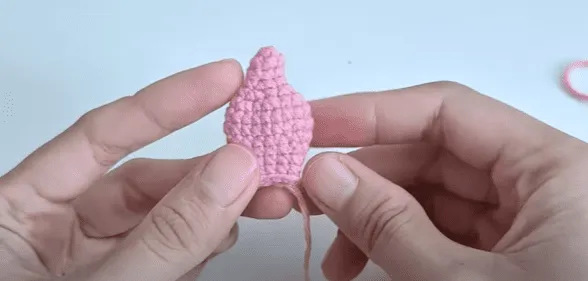 Primer plano de una pieza amigurumi rosa tejida a crochet.