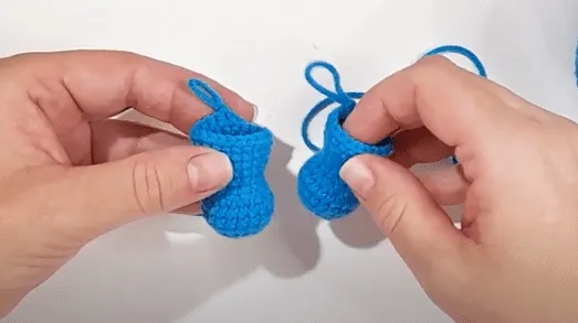 Primer plano de dos pequeños botitas azules tejidas a crochet.
