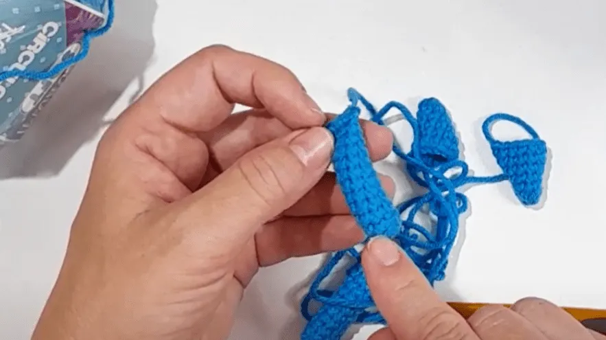 Primer plano de unas manos tejiendo pequeñas sandalias azules