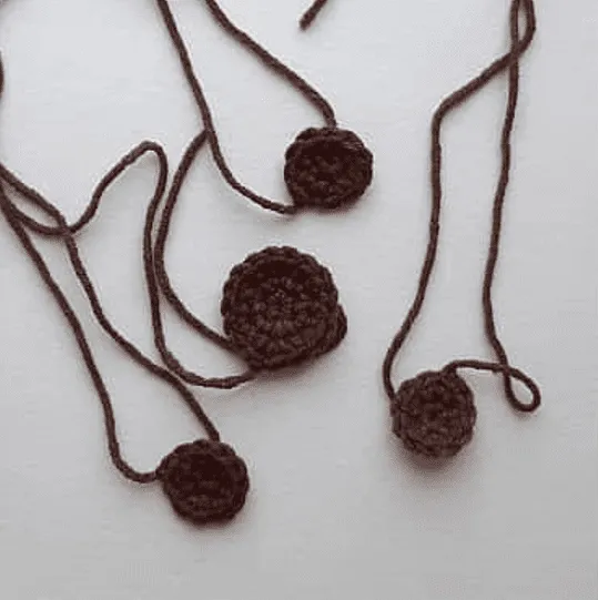 Círculos marrones tejidos a crochet con colas de hilo unidas