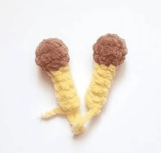 Dos conos de helado tejidos a crochet con tapas marrones y bases amarillas
