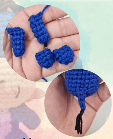 Una Mano Sostiene Dos Pequeñas Formas Azules De Ganchillo Con Hilos Colgando Abajo Otra Mano Sostiene Una Forma Redonda De Crochet Azul Más Grande Con Un Hilo Negro Trenzado En El Extremo La Escena Es Perfecta Para Crochet Para Principiantes Sobre Un Fondo Pastel