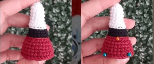 Una Mano Sostiene Un Pequeño Objeto Tejido a Crochet Que Se Asemeja a Un Gnomo Con Un Sombrero Blanco Una Banda Negra Y Un Cuerpo Rojo El Objeto Se Muestra Desde Dos ángulos El Frente Y El Reverso Al Fondo Se Ven Borrosas Hojas Verdes Que Recuerdan a Un Patrón Amigurumi De Alicia En El País De Las Maravillas