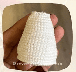 Una Foto De Primer Plano Muestra a Una Persona Sosteniendo Un Pequeño Artículo De Ganchillo En Forma De Cono Hecho De Hilo Blanco La Textura Parece Perfectamente Tejida Asemejándose a Una Creación De Amigurumi En Español El Objeto Se Sostiene Entre El Pulgar Y Los Dedos