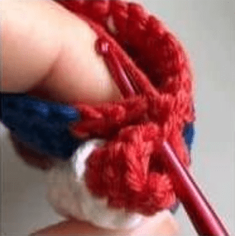 Primer Plano De Una Persona Tejiendo Con Hilo Rojo Y Un Ganchillo Rojo También Se Ven Hilos Blancos Y Azules Lo Que Indica Un Proyecto De Crochet Multicolor Los Dedos De La Persona Manipulan Hábilmente El Hilo Y El Ganchillo Tal Vez Trabajando En Un Patrón Amigurumi De Mario Bros