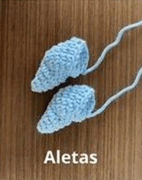 Dos Pequeñas Aletas De Pez De Crochet De Color Azul Claro Colocadas Sobre Una Superficie De Madera Con La Palabra aletas Escrita Debajo Las Aletas Están Conectadas Por Trozos De Hilo Dando Una Idea De Cómo Hacer Creaciones De Amigurumi Como Estas O Incluso Un Amigurumi Cohete