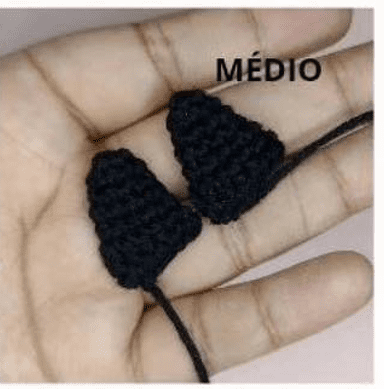 Una Mano Sostiene Dos Pequeños Artículos Negros Tejidos a Mano Con Puntas Puntiagudas Y Cordones Atados La Palabra mÉdio Está Escrita En Texto Negro Encima De Los Objetos Asemejándose a Un Patrón Amigurumi De La Serie De Amigurumi Dragón Ball