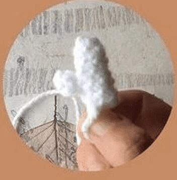 Mano Sosteniendo Un Artículo Pequeño Blanco Tejido O Tejido a Ganchillo Sobre Un Fondo Con Un Diseño Tenue De árbol O Valla La Atención Se Centra En La Pieza Artesanal Hecha a Mano Siguiendo El Método Amigurumi Paso a Paso