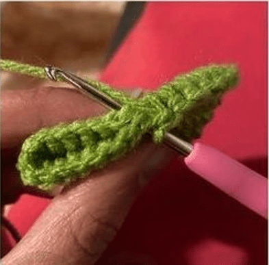 Primer Plano De Una Persona Tejiendo Con Un Ganchillo De Mango Rosa E Hilo Verde El Trabajo De Crochet Está Parcialmente Terminado Y Se Ven Claramente Los Puntos Y La Textura Del Hilo