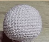Primer Plano De Un Objeto Esférico Tejido a Mano En Crochet Probablemente De Hilo De Color Claro El Fondo Es Una Superficie Plana Posiblemente Una Mesa De Madera
