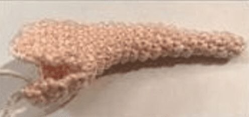 Primer Plano De Un Objeto Texturizado De Color Beige Que Se Asemeja a Un Trozo De Tejido De Crochet O De Punto Parcialmente Enrollado El Fondo Es Una Superficie Pálida Y Neutra