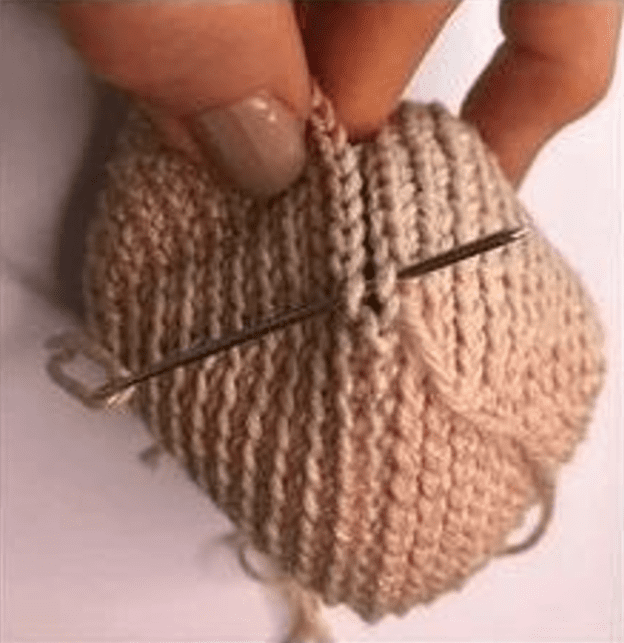 Imagen En Primer Plano De Una Mano Cosiendo Con Una Aguja E Hilo De Color Claro La Aguja Atraviesa Un Trozo De Tela Tejida a Crochet O De Punto Lo Que Indica Un Trabajo Artesanal Detallado