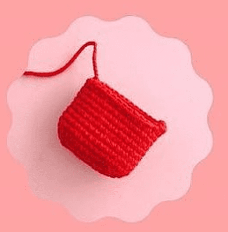 Una Pequeña Porción De Trabajo De Crochet Rojo Mostrado Sobre Un Fondo Rosa Claro Con Una Superposición Circular Blanca Con Bordes Festoneados La Pieza Parece Estar En Progreso Con Un Hilo Suelto Que Se Extiende Desde La Esquina Superior Izquierda