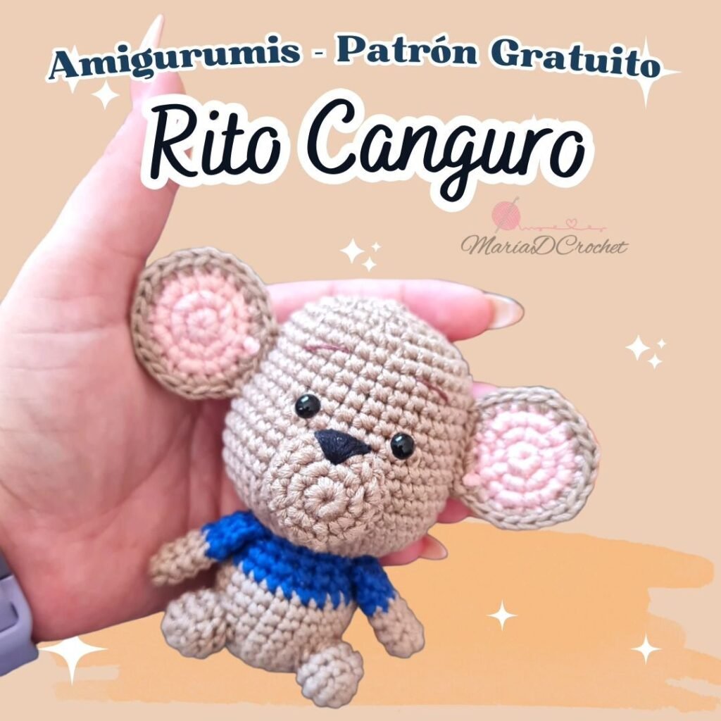 Una mano que sostiene un amigurumi canguro tejido a crochet con grandes orejas rosas y una camisa azul. El texto de arriba dice "Amigurumis - Patrón de Crochet Canguro" con un pequeño ícono de corazón y el nombre "MariaDCrochet" debajo. El fondo es claro con pequeñas estrellas.